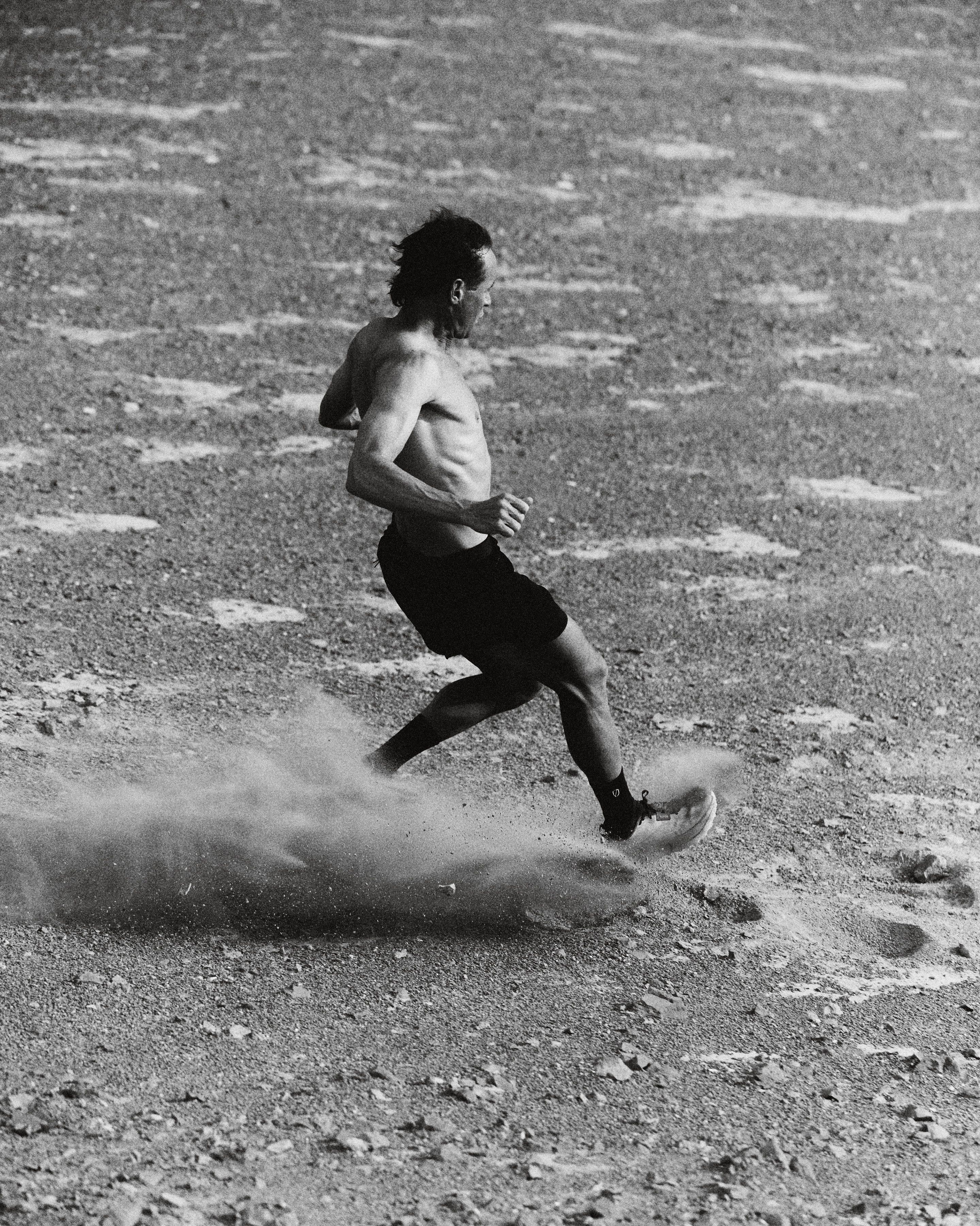 A lone runner crossing open ground, dust trailing behind the back foot