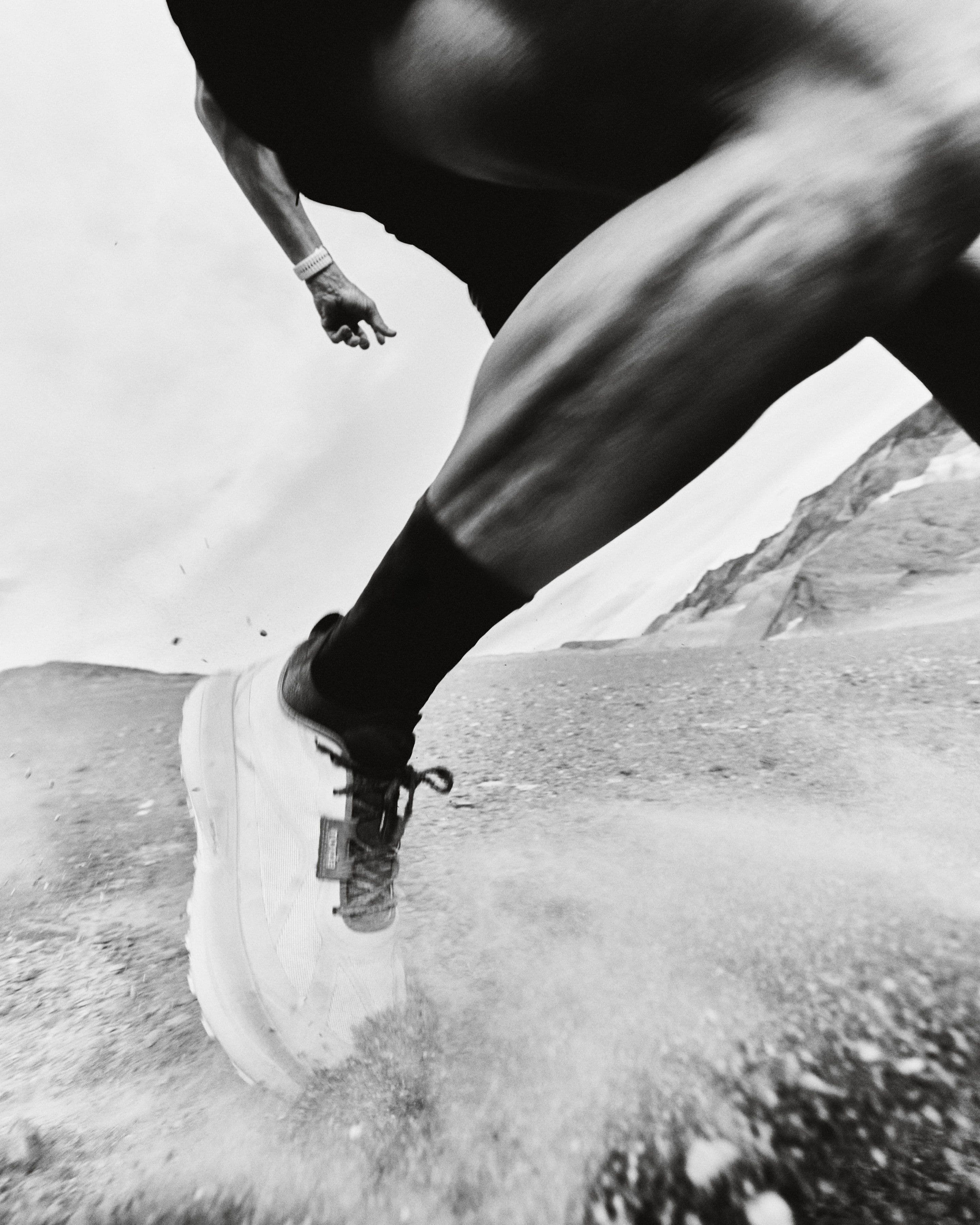 A low tracking shot at ankle height as a runner drives off loose ground