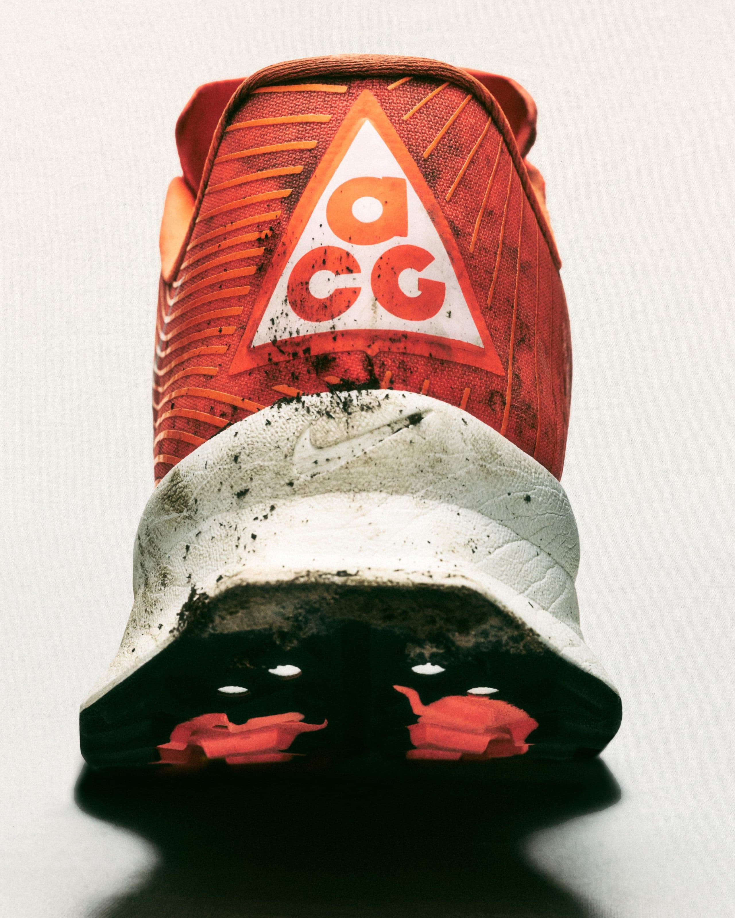 The heel of a mud-spattered ACG Ultrafly: an orange counter with a large white ACG triangle
