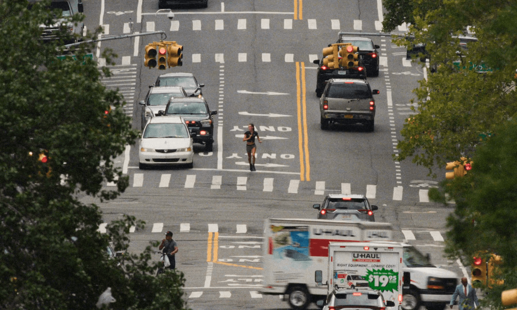 125th Street seen from above: a lone runner in the turn-only lane between six lanes of traffic, a U-Haul in the foreground