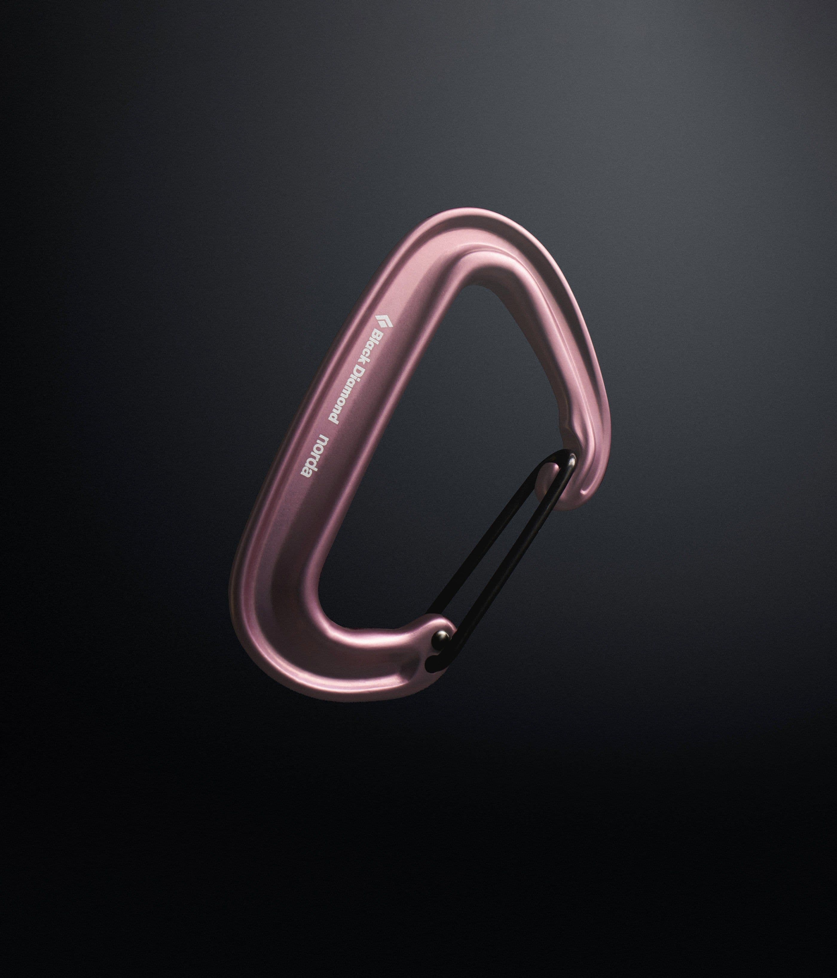 A pink Miniwire carabiner on a black ground, etched Black Diamond and norda along the spine