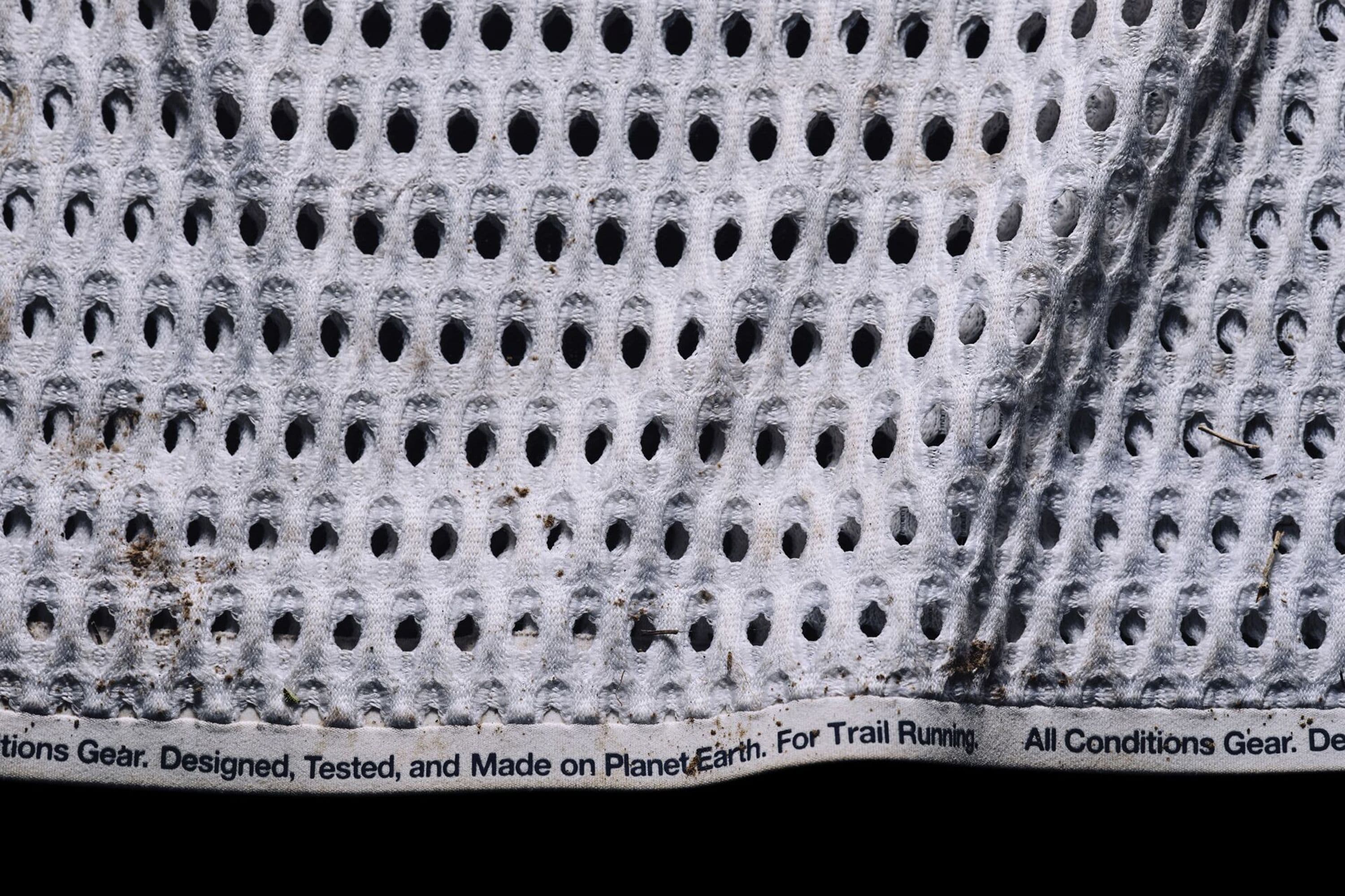 Close-up of the cropped hem of the prototype, dirt-stained, with the printed line “Designed, Tested, and Made on Planet Earth. For Trail Running.”